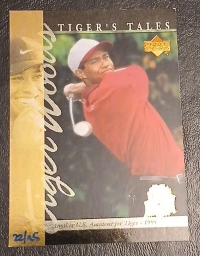 Independent seller reference of Tiger Woods Tiger's Tales TT10, the 2026 25th Anniversary stamped buyback of the 2001 card, hand-numbered 22/25. Tiger wears a red shirt; the commemorative stamp has glare. This is not an autograph.