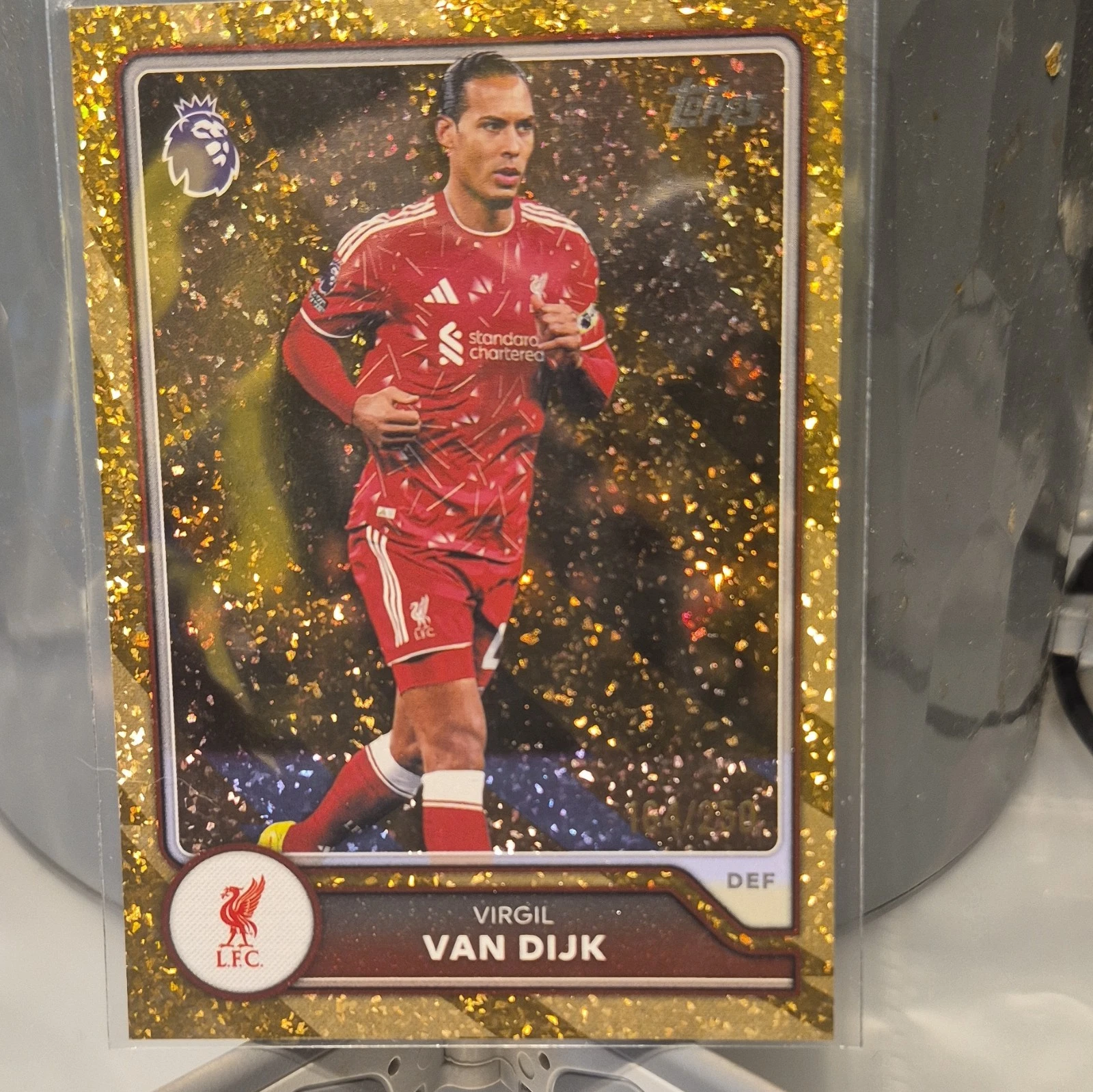Actual independent photograph of Virgil van Dijk 2026–27 Topps Premier League #162 with a gold flake foil border, wearing a red Liverpool kit. Reference copy 164/250 is different from the requested 219/250 card.